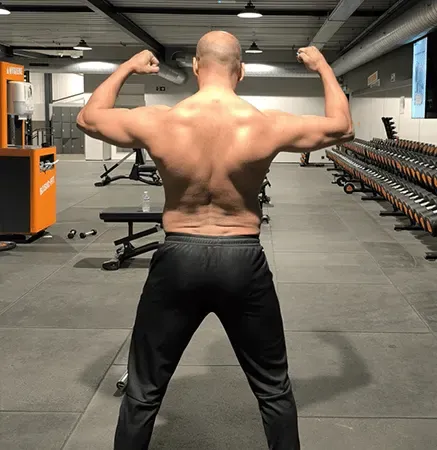Ashish van achteren gezien, met beide armen omhoog en aangespannen rugspieren