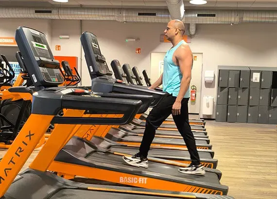 Ashish stapt op een loopband, in een rij cardiotoestellen
